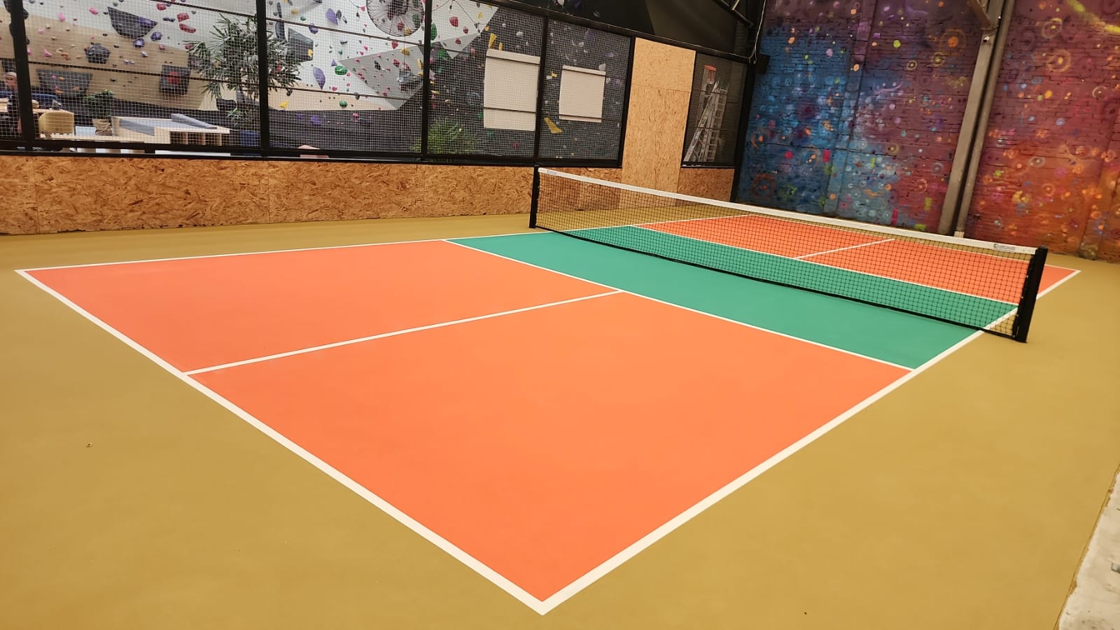Cancha de pickleball indoor construida en gimnasio con colores naranja y verde sistema tipo Laykold